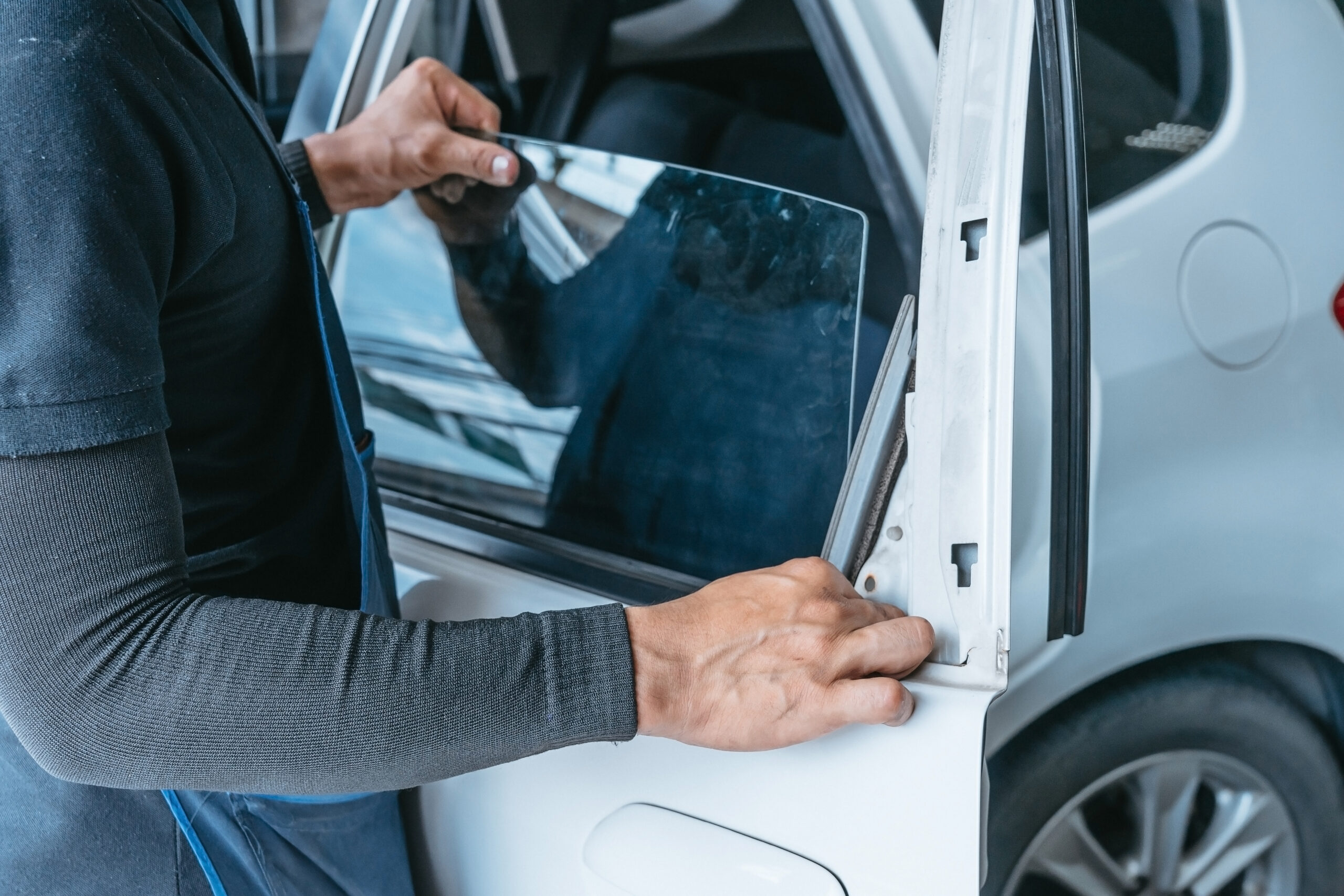 Mechanics man changing the broken windshield and automobile windshield or windscreen replacement of white car in Auto Repair Shop